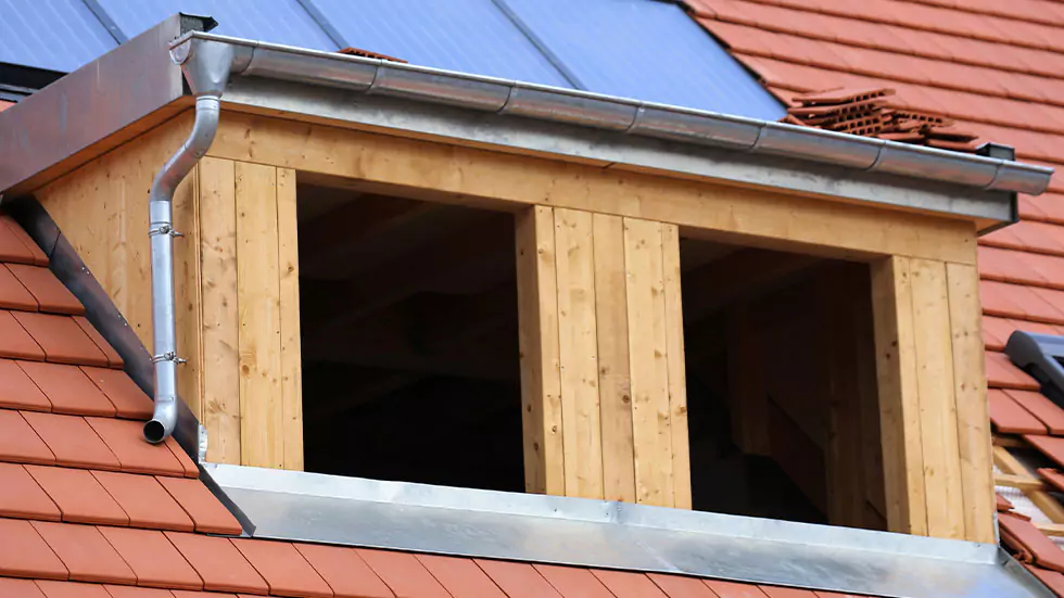 Nahaufnahme einer Dachgaube im Bau aus Holz mit Metallverkleidung und Regenrinne