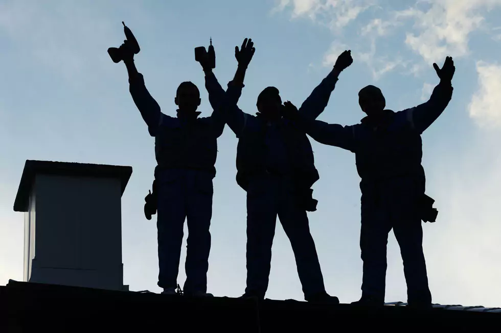 Dachdeckerteam auf einem Dach Silhouette